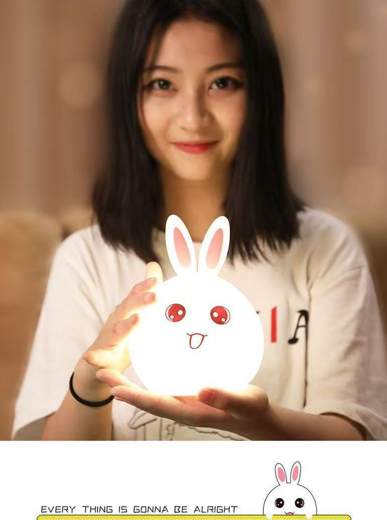 Person holding a glowing rabbit-shaped night light with Chinese text and branding.