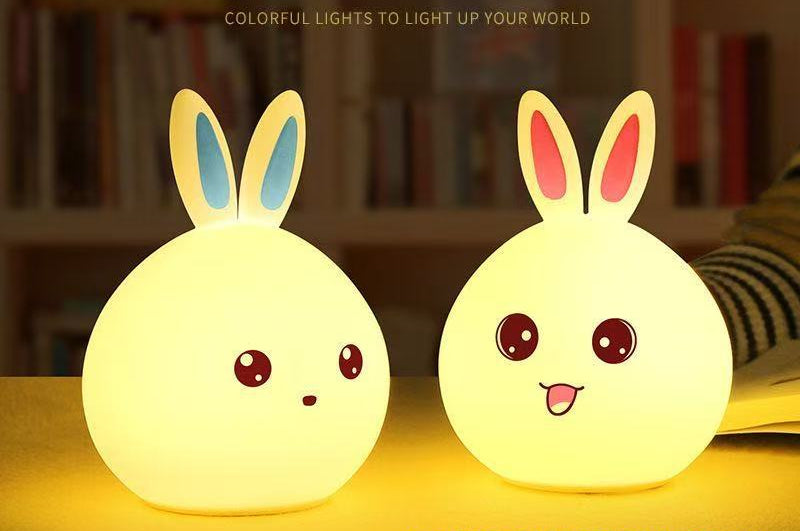 Two cartoon rabbit-shaped night lights on a yellow surface with text in the background.